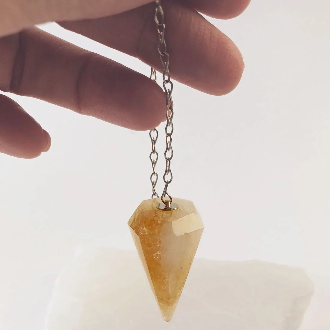A citrine crystal point pendulum with chain