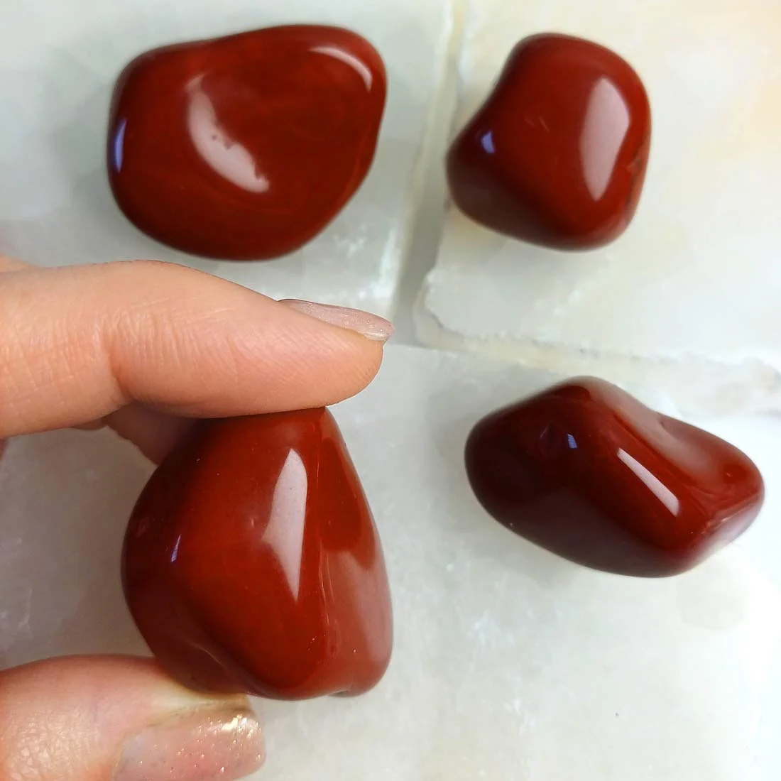 Natural Red Jasper tumbled stones with deep earthy red tones and smooth polished surfaces.