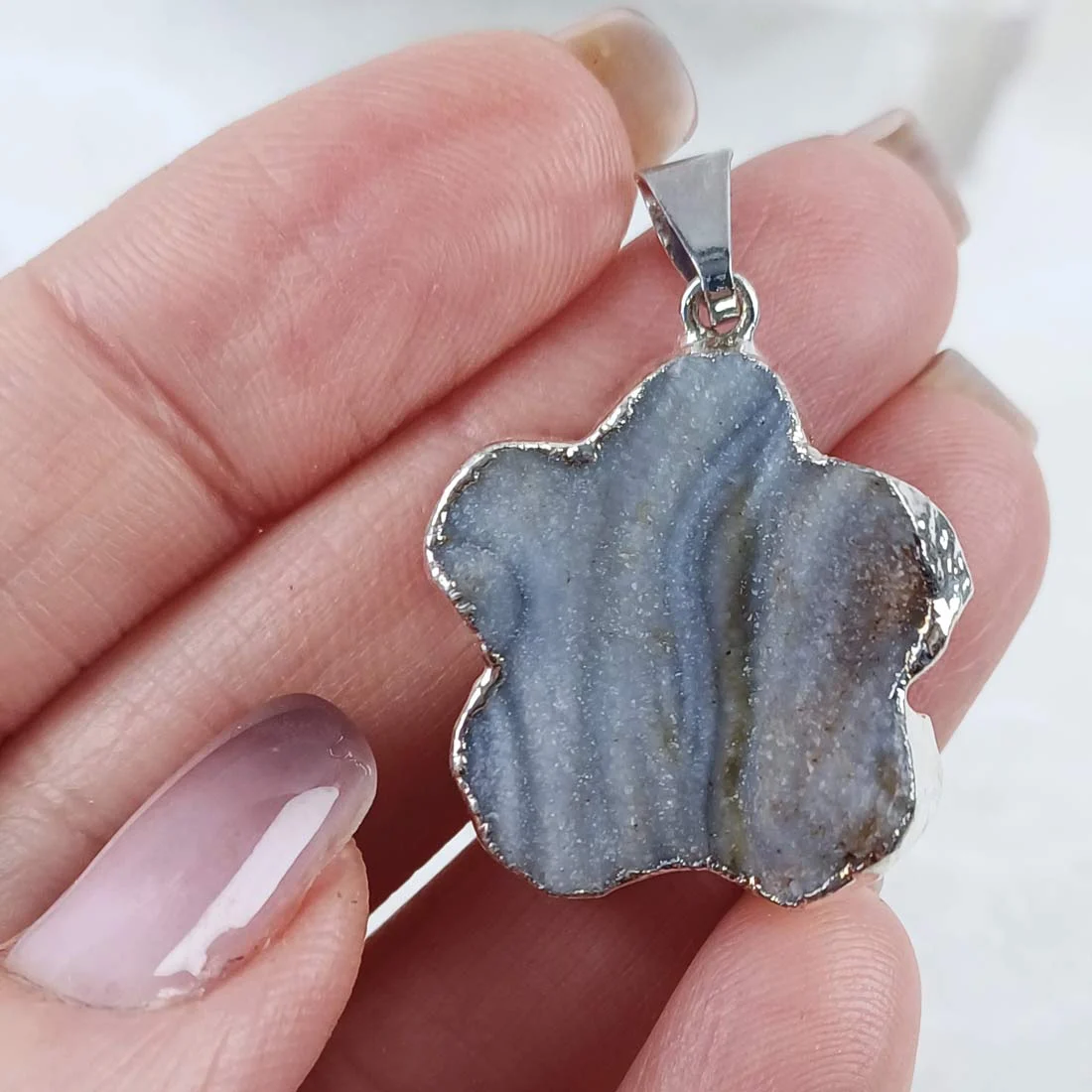 Chalcedony flower shaped pendants with natural grey-blue banding set in silver plated metal.