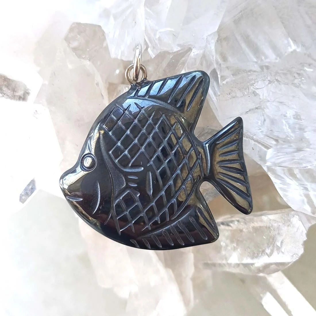 Fish-shaped pendant carved from polished hematite crystal. The piece features engraved details and a metallic hook (not sterling silver) for attaching to a chain or cord.
