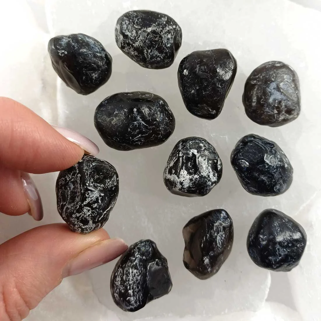 Natural Obsidian nodules with deep black volcanic glass surface and organic shapes, grounding crystal associated with protection and stability.