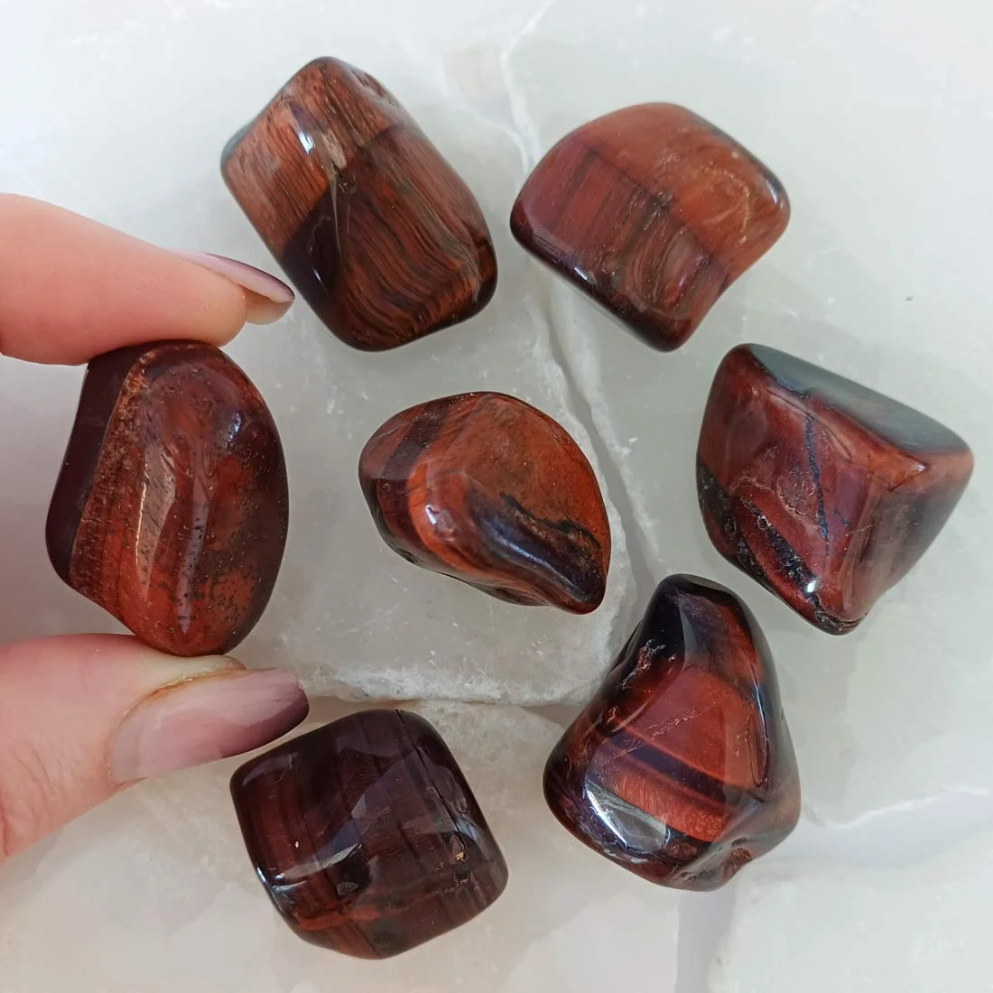 Polished Red Tiger Eye tumbled stone with deep reddish brown tones and silky chatoyant bands, crystal associated with motivation and confidence