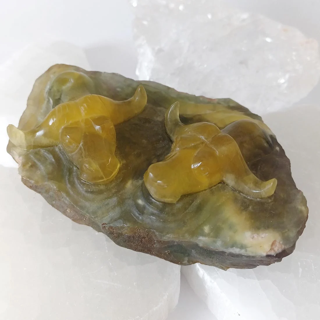 Fluorite oxen carving in yellow and olive green tones, palm-sized crystal with ox emerging from water-like base