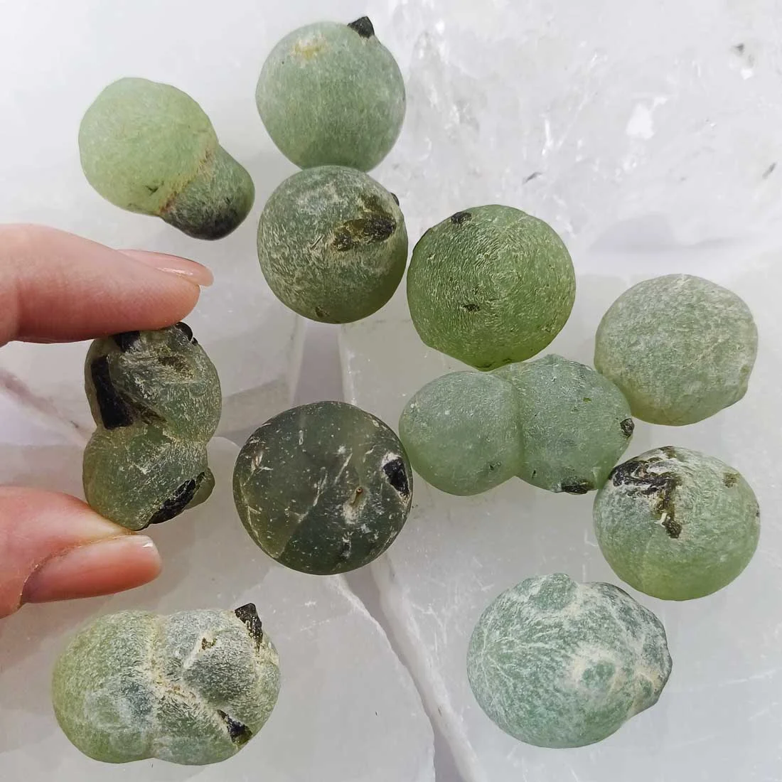 Prehnite with Epidote natural rough crystal showing green botryoidal formations with dark inclusions on white background