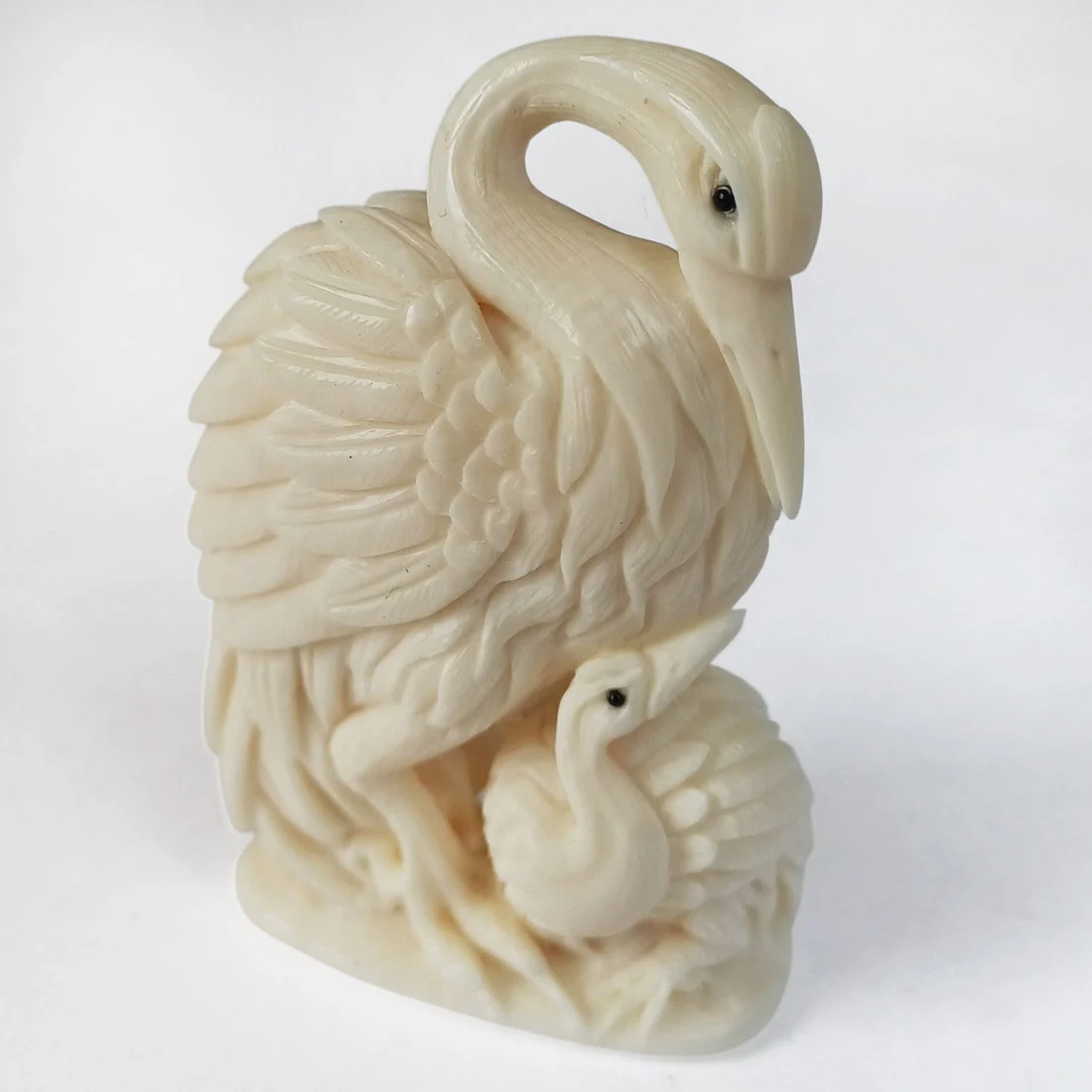 Palm-sized mammoth ivory carving of a crane with its chick, signed by the carver in traditional lettering, collectible fossil ivory sculpture
