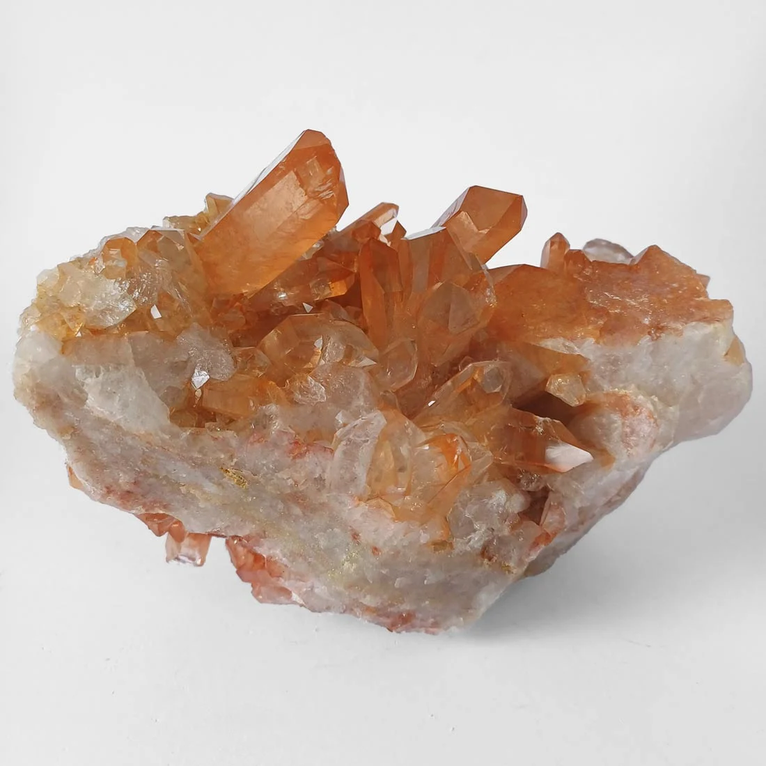 Natural Tangerine Quartz crystal cluster with orange iron-coated quartz points on raw mineral base