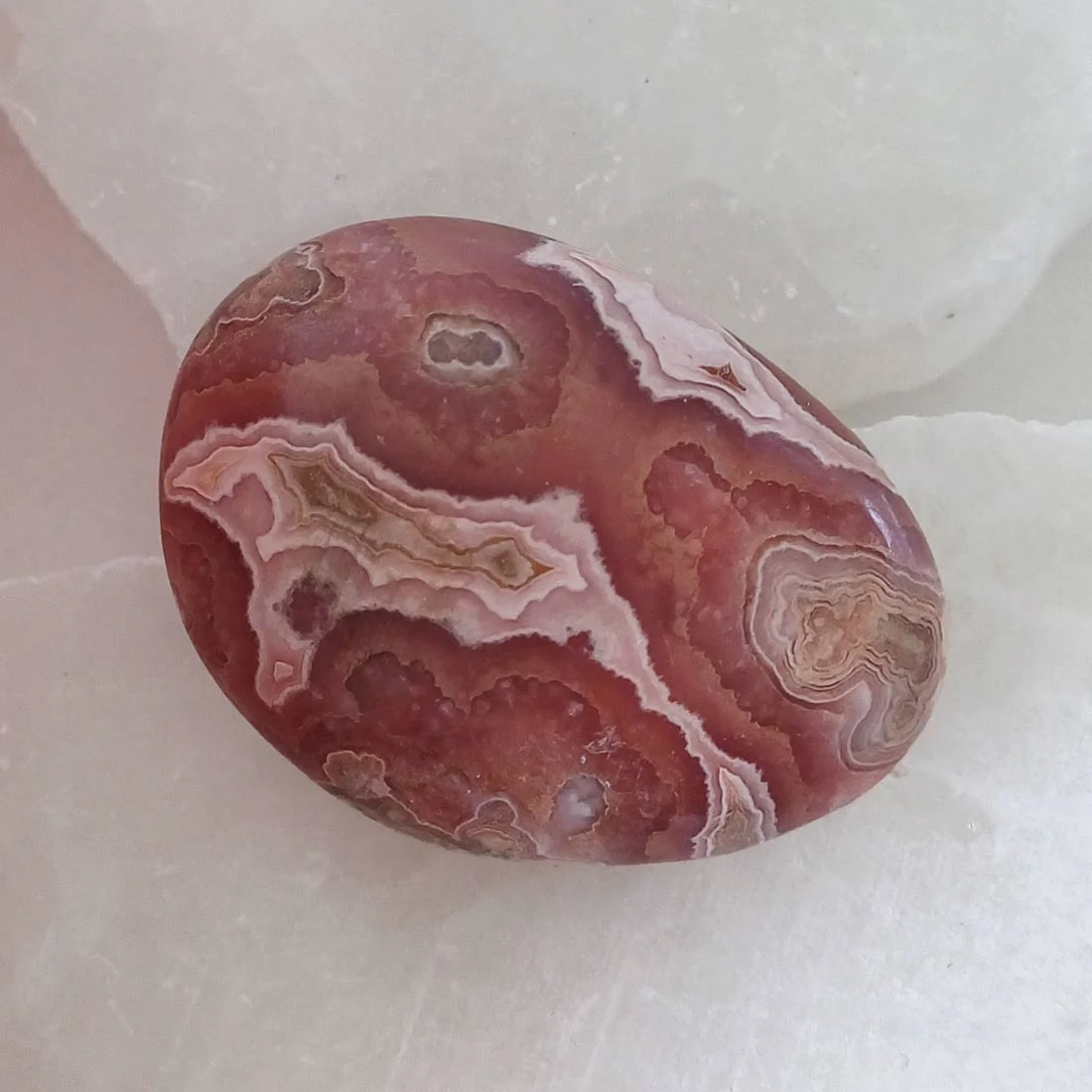 Natural Rhodochrosite palm stone with layered pink and cream formations
