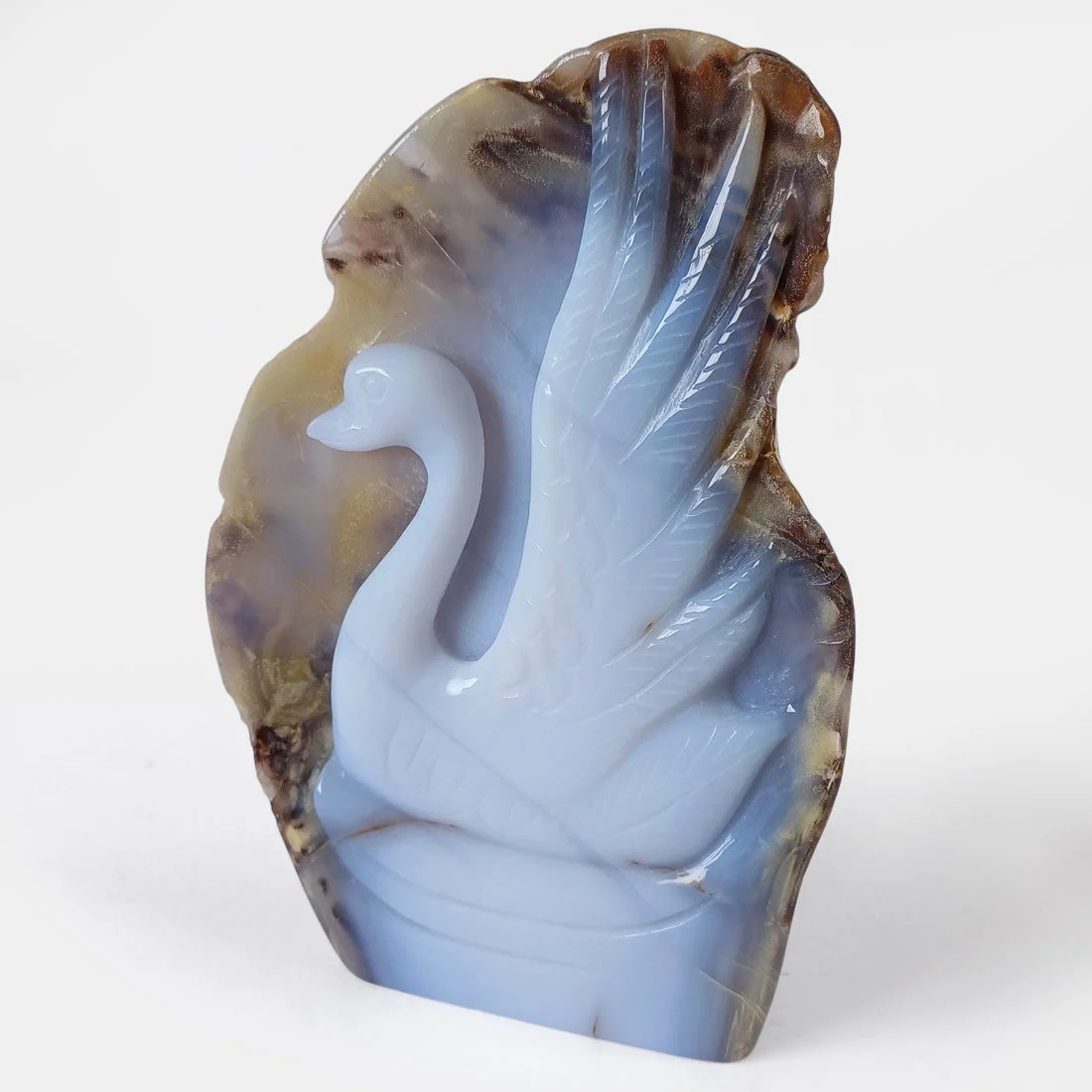 Carved swan figure made from a halved chalcedony slice showing earthy outer stone and smooth white-blue interior.