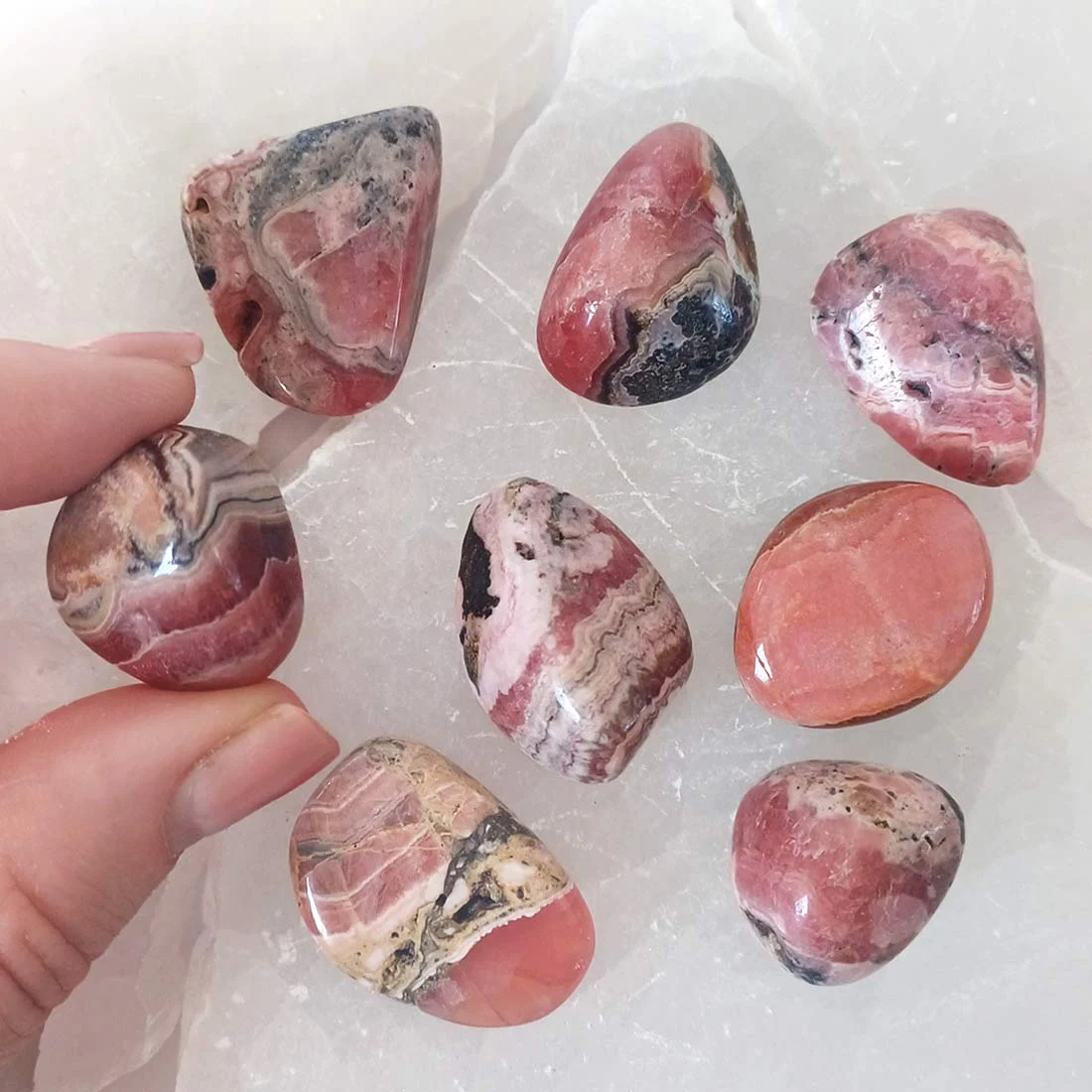 Polished Rhodochrosite tumbled stone with natural pink and cream banded patterns