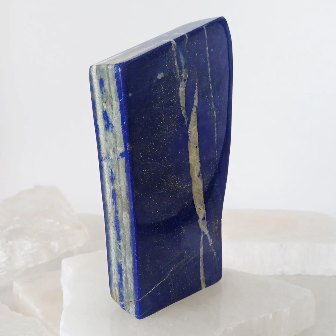 Polished self-standing Lapis Lazuli mineral from Pakistan with deep blue color and natural pyrite inclusions.