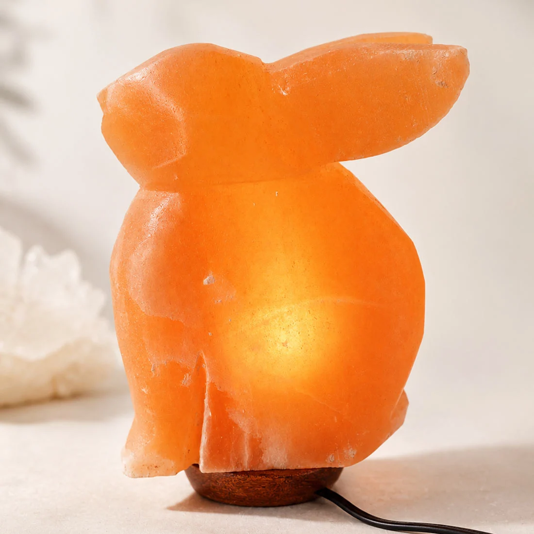 Hand-carved Rabbit Himalayan Salt Lamp made from natural Himalayan rock salt with a warm amber glow on a wooden base.