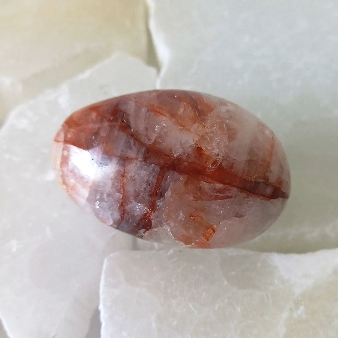 Red Hematoid Quartz palm stone with red and orange iron-rich inclusions and a smooth polished surface